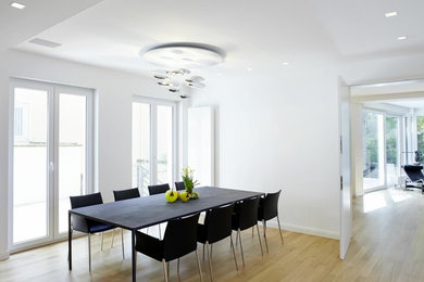 Geschlossenes Modernes Esszimmer mit weißer Wandfarbe und hellem Holzboden in Hannover