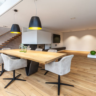 Offenes, Großes Modernes Esszimmer mit grauer Wandfarbe, hellem Holzboden, Eckkamin, verputzter Kaminumrandung und beigem Boden in Sonstige