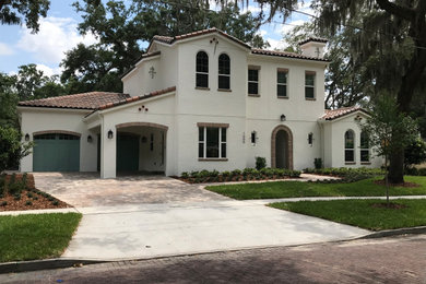 Mid-sized mediterranean white two-story stucco house exterior idea in Orlando with a hip roof and a tile roof