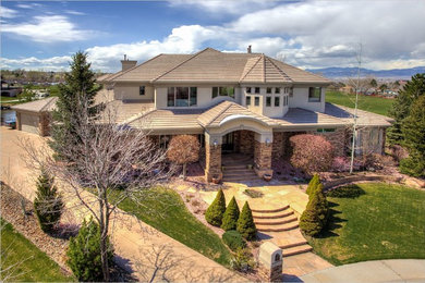 Huge mediterranean beige two-story stucco exterior home idea in Denver with a hip roof