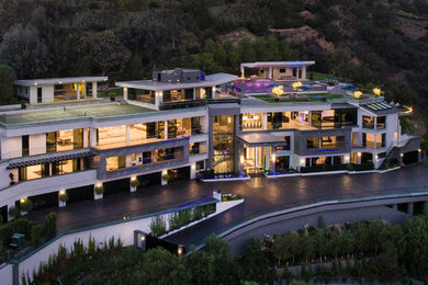 ロサンゼルスにあるラグジュアリーな巨大なモダンスタイルのおしゃれな家の外観 (石材サイディング、混合材屋根) の写真