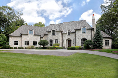 Example of a huge classic gray two-story stone house exterior design in Chicago with a hip roof and a shingle roof