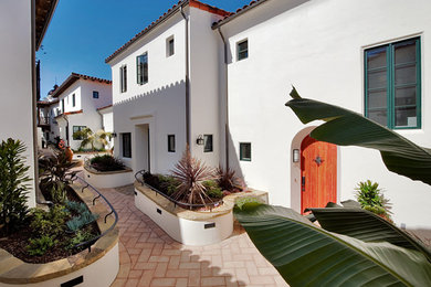 Example of a large tuscan white two-story stucco exterior home design in Santa Barbara with a hip roof and a tile roof