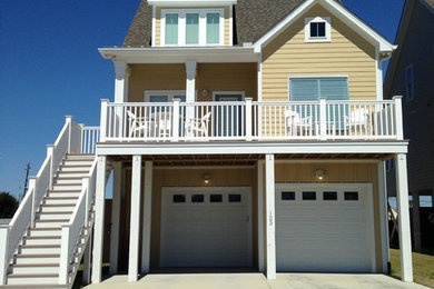 Example of a large beach style yellow two-story wood gable roof design in Other