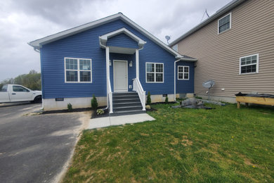 Foto på ett stort funkis blått hus, med allt i ett plan, vinylfasad, sadeltak och tak i shingel