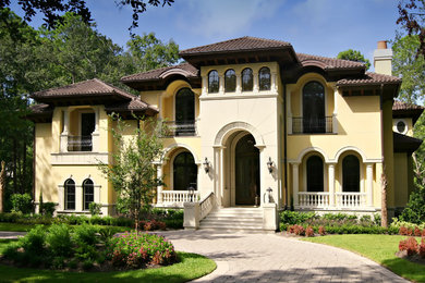 Huge mediterranean yellow two-story stucco exterior home idea in Charleston with a hip roof