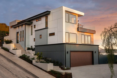 Diseño de fachada de casa gris actual extra grande de tres plantas con revestimientos combinados, tejado plano y tejado de teja de madera