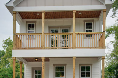 Modelo de fachada de casa blanca tradicional renovada de dos plantas con revestimiento de madera y tejado a dos aguas