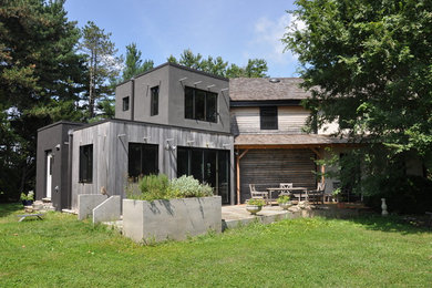 Réalisation d'une petite façade de maison grise minimaliste à un étage avec un revêtement mixte.