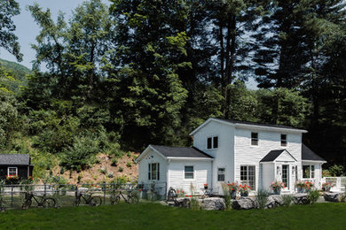 Immagine della facciata di una casa grande bianca country a due piani con rivestimento in legno e copertura a scandole