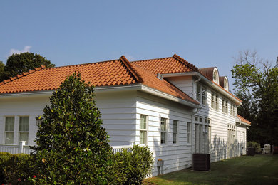 Imagen de fachada de casa blanca mediterránea extra grande de dos plantas con tejado a cuatro aguas, tejado de teja de madera y revestimiento de vinilo