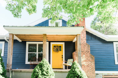 Modelo de fachada de casa azul campestre pequeña de una planta con revestimiento de madera y tejado a dos aguas