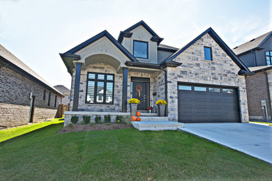 Country gray two-story stone exterior home photo in Toronto with a shingle roof