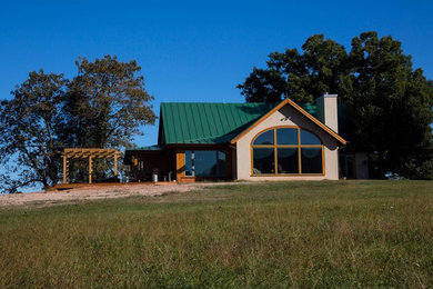 Imagen de fachada de casa de estilo americano de una planta con revestimientos combinados y tejado de metal