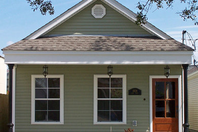 Ejemplo de fachada de casa verde tradicional pequeña de una planta con revestimiento de vinilo, tejado a dos aguas y tejado de teja de madera