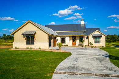Imagen de fachada de casa marrón campestre grande de una planta con revestimientos combinados, tejado a dos aguas y tejado de metal