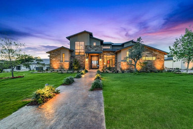Large trendy beige two-story stone exterior home photo in Austin with a metal roof