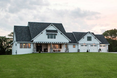 Aménagement d'une grande façade de maison blanche campagne à un étage avec un revêtement mixte, un toit à quatre pans et un toit en shingle.