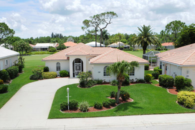 Mid-sized tuscan white one-story stucco house exterior photo in Tampa with a hip roof and a tile roof