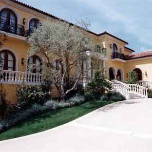 Modelo de fachada amarilla, mediterránea, extra grande, de tres plantas, con revestimiento de estuco y tejado a cuatro aguas