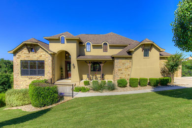 Example of a transitional beige two-story stucco exterior home design in Austin with a clipped gable roof