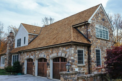 Example of a large classic beige split-level stone gable roof design in Philadelphia