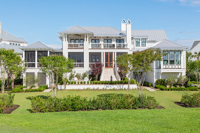 Example of a beach style beige three-story wood house exterior design in Charleston with a hip roof and a metal roof