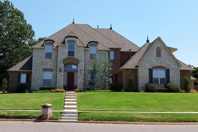 Example of a huge classic beige two-story mixed siding house exterior design in Oklahoma City with a hip roof and a shingle roof