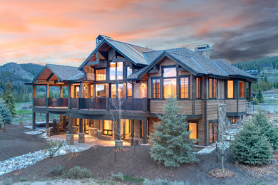 Large mountain style brown two-story wood exterior home photo in Denver with a clipped gable roof