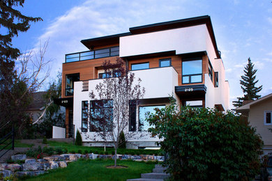 Diseño de fachada blanca moderna de tamaño medio de tres plantas con revestimiento de estuco y tejado plano