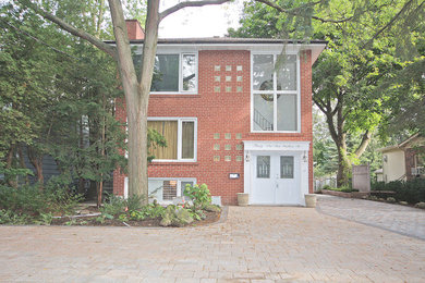 Ejemplo de fachada de casa bifamiliar roja clásica de tamaño medio de dos plantas con revestimiento de ladrillo, tejado a dos aguas y tejado de teja de madera