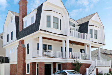 Inspiration for a large coastal white three-story wood house exterior remodel in Philadelphia with a gambrel roof and a mixed material roof