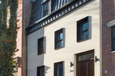 Ejemplo de fachada de casa pareada beige contemporánea con revestimiento de ladrillo y tejado de metal