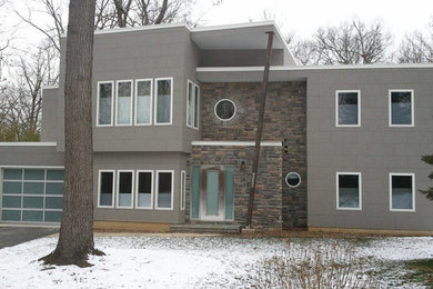 Foto på ett mellanstort funkis grått hus, med två våningar, blandad fasad och platt tak