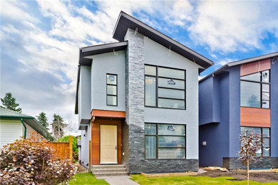Mid-sized contemporary blue two-story stucco house exterior idea in Calgary with a shingle roof