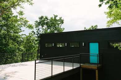 Example of a mid-sized minimalist black three-story concrete fiberboard flat roof design in Other