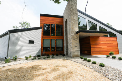 На фото: одноэтажный частный загородный дом в стиле модернизм с комбинированной облицовкой и металлической крышей с