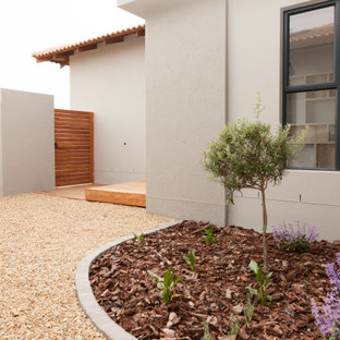 Diseño de fachada de casa beige, de tamaño medio, de una planta, con revestimiento de hormigón, tejado a dos aguas y tejado de teja de barro