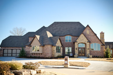 Huge elegant red two-story mixed siding house exterior photo in Oklahoma City with a hip roof and a shingle roof