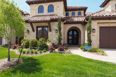 Large tuscan beige two-story stone exterior home photo in Dallas with a hip roof