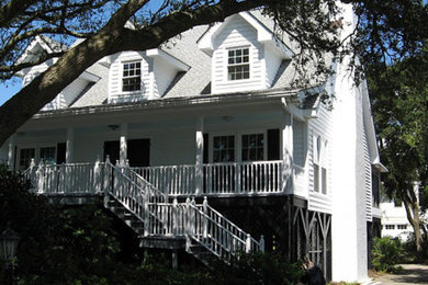 Esempio della facciata di una casa grande bianca classica a tre piani con rivestimento in legno e tetto a capanna