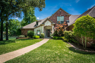 Example of a classic red two-story brick exterior home design in Austin