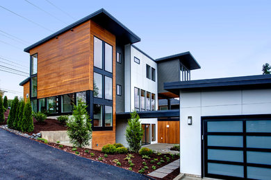 Ejemplo de fachada gris actual de tamaño medio de tres plantas con revestimiento de madera y tejado plano