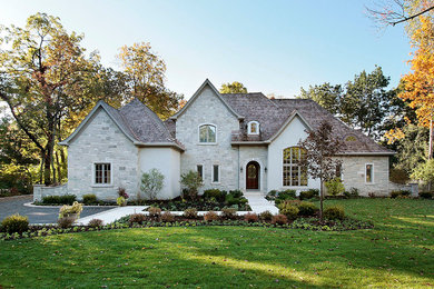 Стильный дизайн: большой, двухэтажный, серый частный загородный дом в классическом стиле с облицовкой из камня, вальмовой крышей и крышей из гибкой черепицы - последний тренд