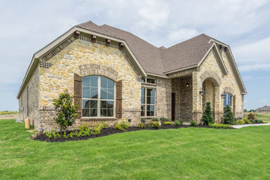 Example of a mid-sized mountain style beige one-story brick house exterior design in Dallas with a clipped gable roof and a shingle roof