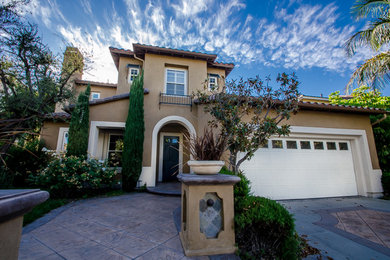 Large trendy beige two-story stucco gable roof photo in Orange County