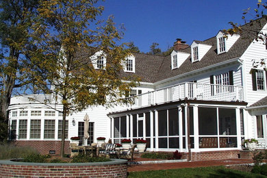Esempio della villa grande bianca classica a due piani con rivestimento in vinile, tetto a capanna e copertura a scandole