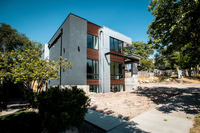 Cette photo montre une grande façade de maison grise tendance en bois à un étage avec un toit plat et un toit en métal.