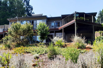 Diseño de fachada de casa gris grande de dos plantas con revestimientos combinados, tejado a dos aguas y tejado de metal