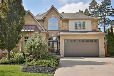 This is an example of a medium sized and beige traditional two floor detached house in Toronto with stone cladding, a hip roof and a shingle roof.